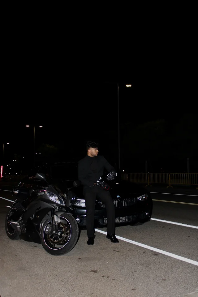 Portrait with a motorcycle and BMW beside illuminated glass architecture