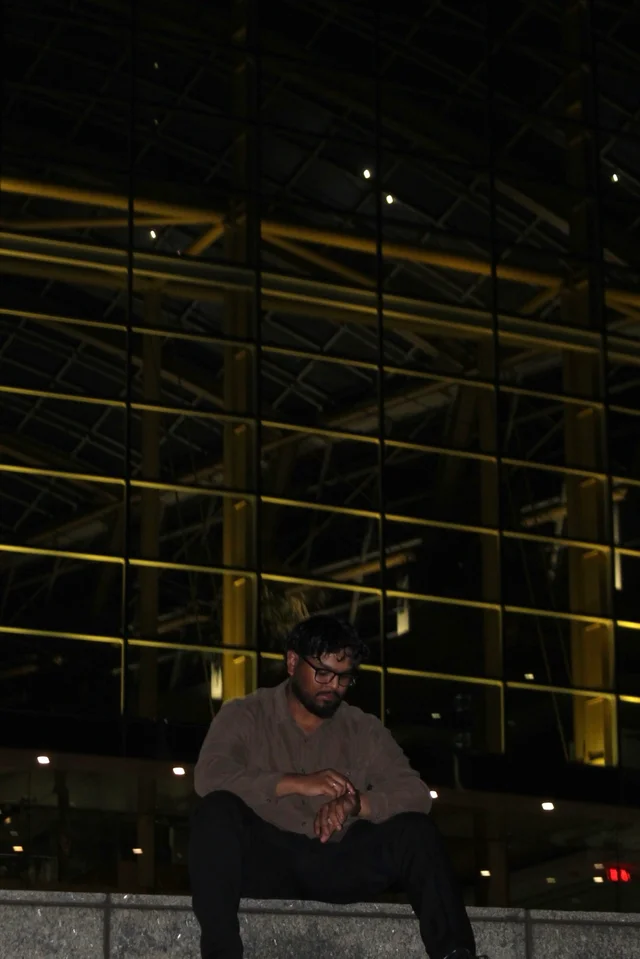 Seated portrait beside illuminated modern architecture at night