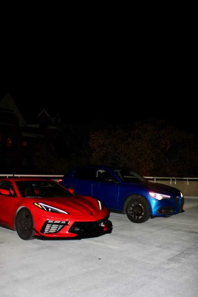 Red Corvette and blue Alfa Romeo parked together at night